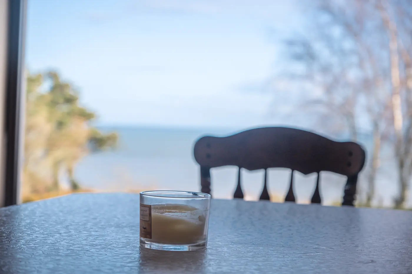 A candle on the table with the sea behind