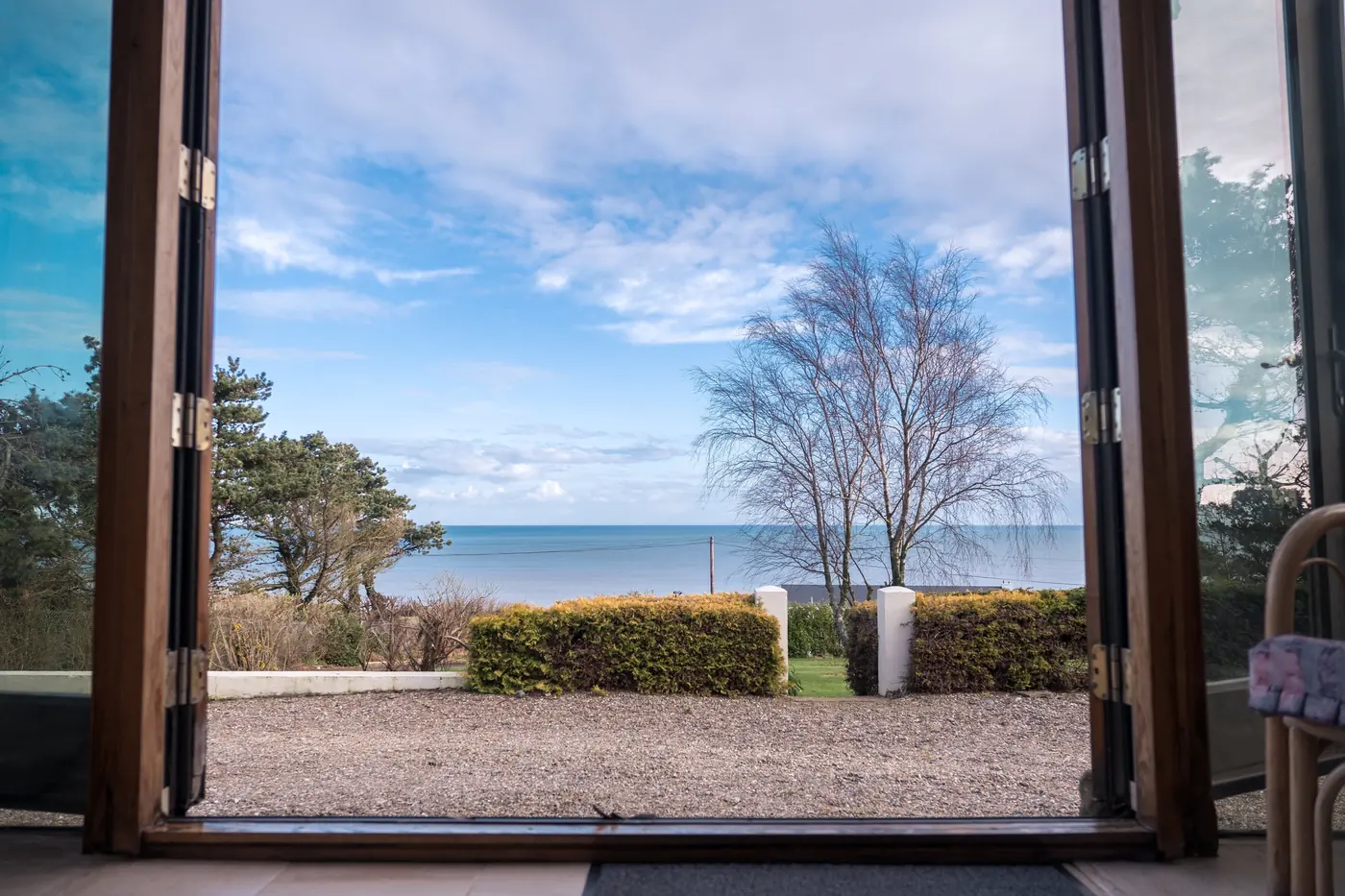 Conservatory doors open to the garden and the sea